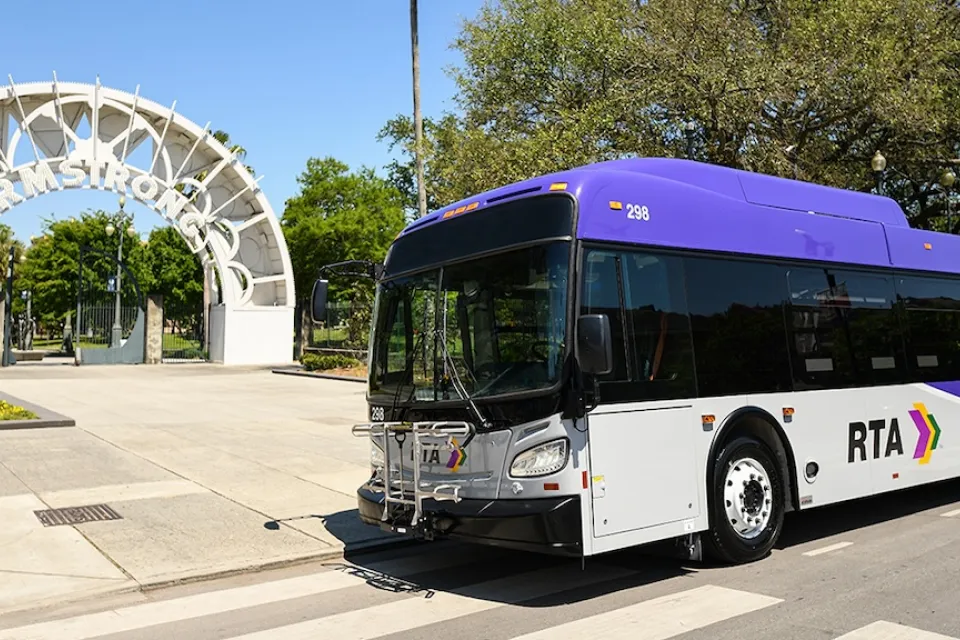 White and purple RTA bus inf ront of white archway to Armstrong transit station in New Orleans, Louisiana.